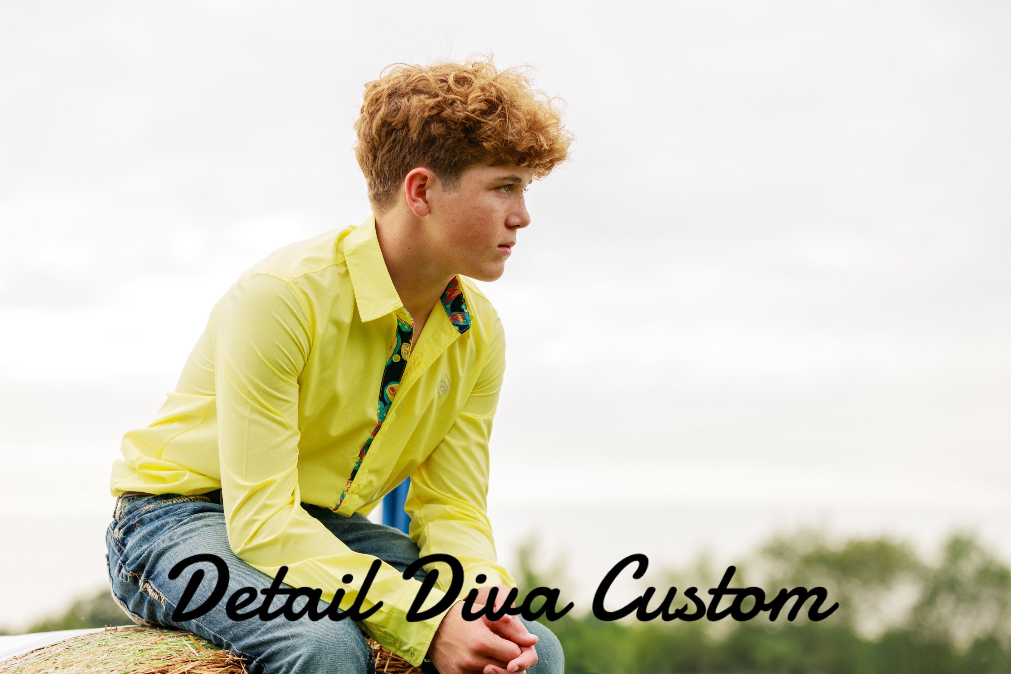 Boy sitting on a hay bale in a yellow shirt.